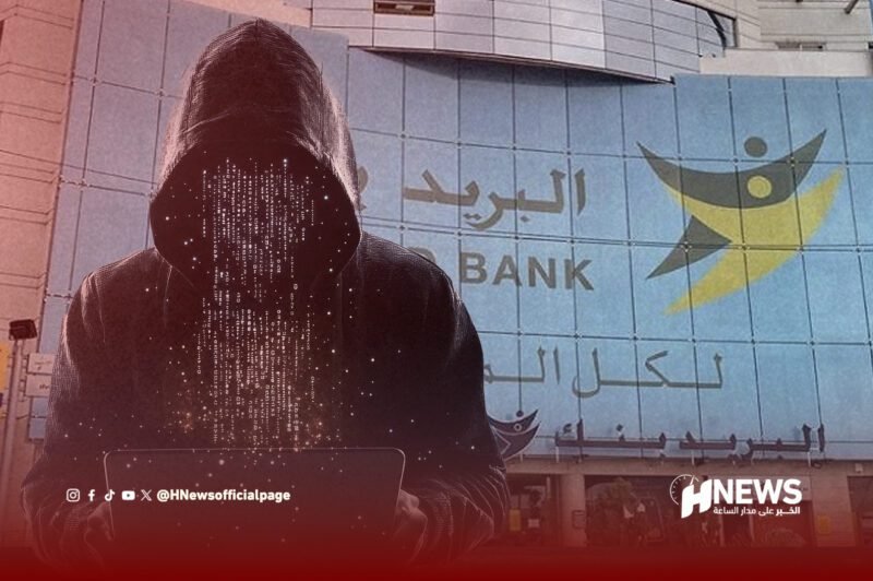 Hooded figure typing on a laptop in front of a bank with Arabic signage, suggesting cybercrime awareness (HNews watermark)