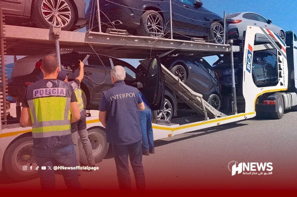 Interpol and police officers inspect a car carrier trailer loaded with several cars on two levels, during a daytime operation