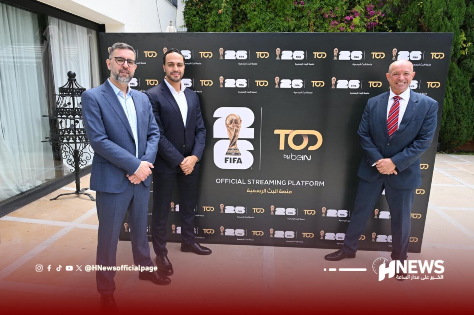 Three men in suits pose for a photo in front of a black backdrop covered with FIFA and TOP by beIN logos at an official streaming event.