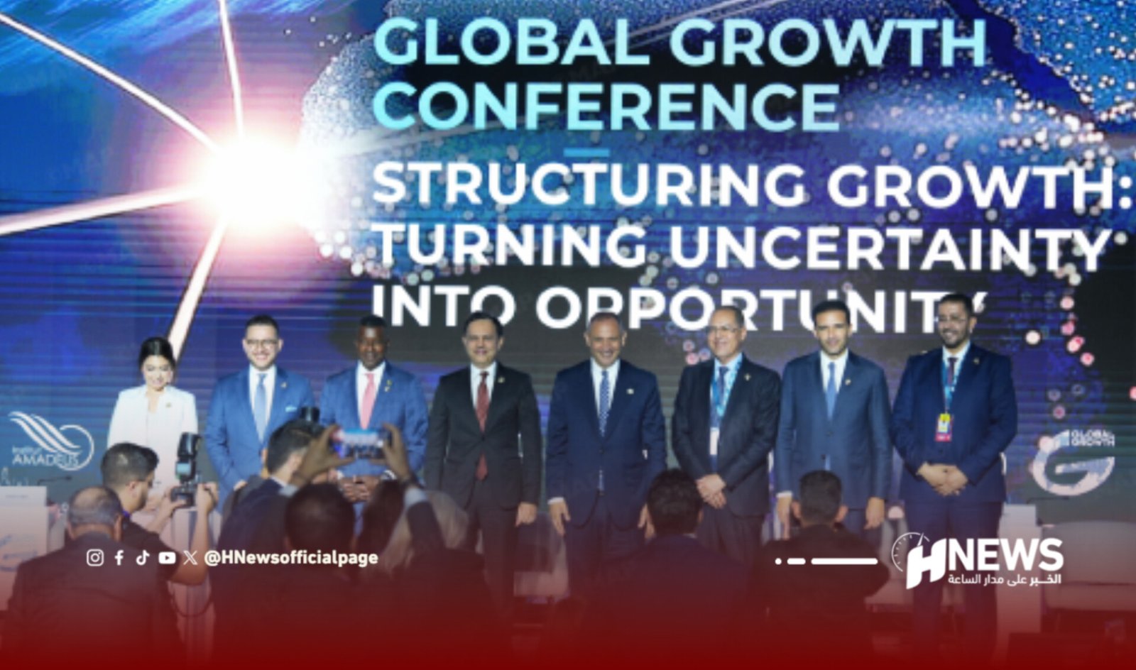 Group of eight business professionals on stage at a conference with photographers in front; backdrop reads 'Global Growth Conference'.