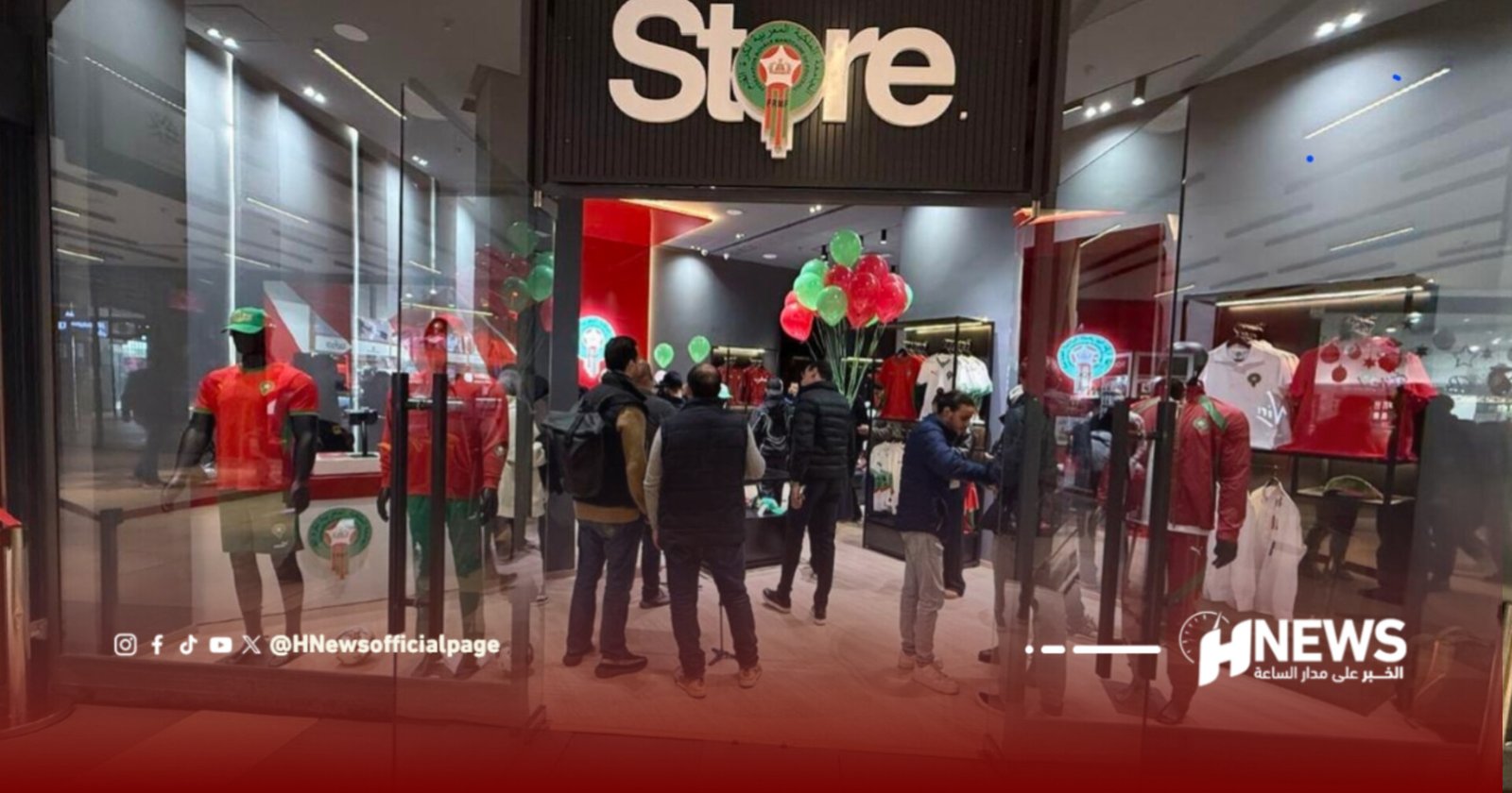 Crowd gathers inside a clothing store during a launch, mannequins wear red outfits and red-green balloons hover above the display shelves, with a bold Store sign above the entrance.