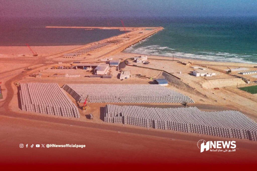 ميناء الداخلة الأطلسي | H-NEWS آش نيوز Coastal construction site with a long pier extending into the sea and hundreds of stacked concrete blocks for a breakwater