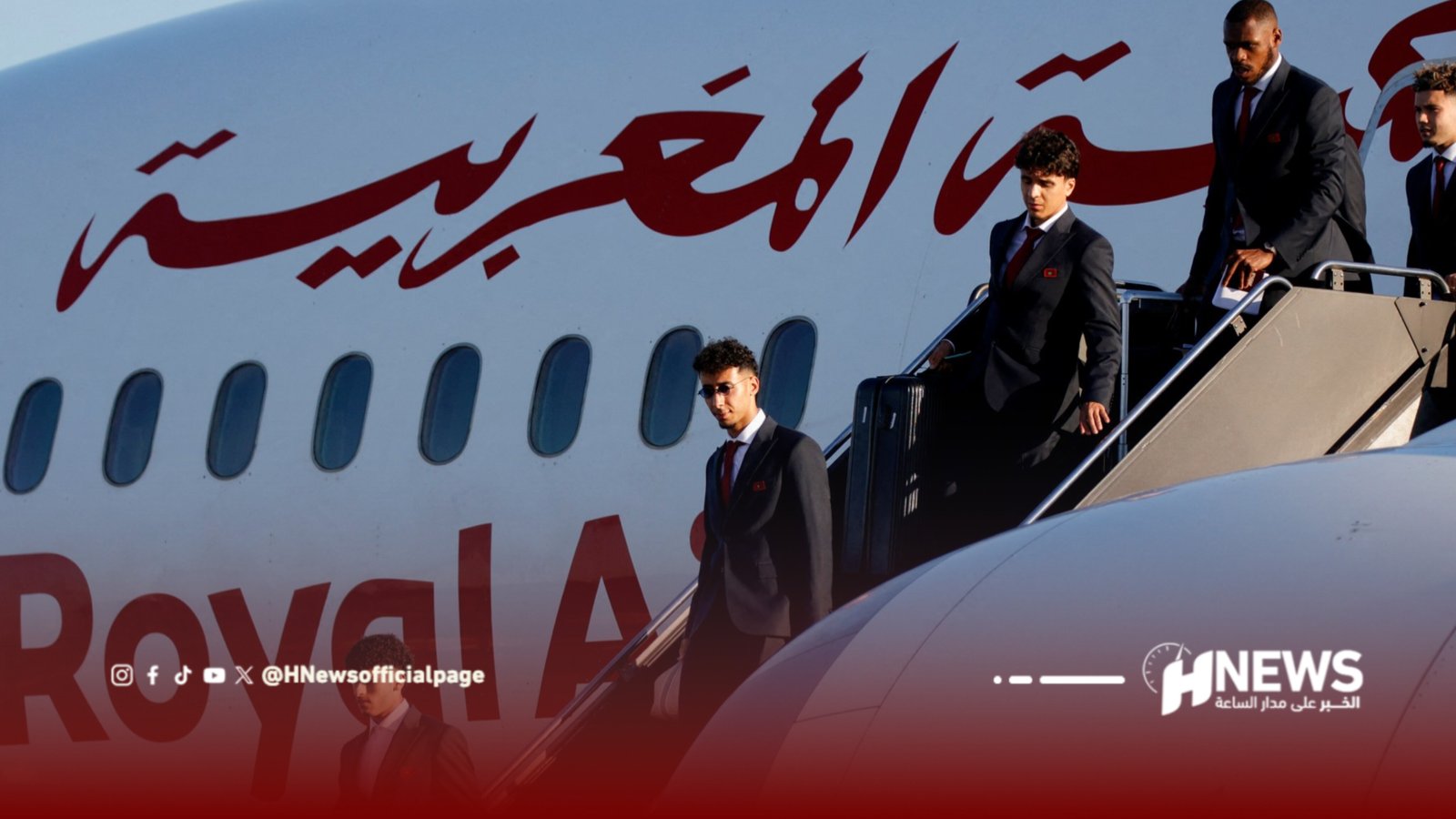 Men in dark suits descend the airplane stairs next to a white plane with large red Arabic writing.