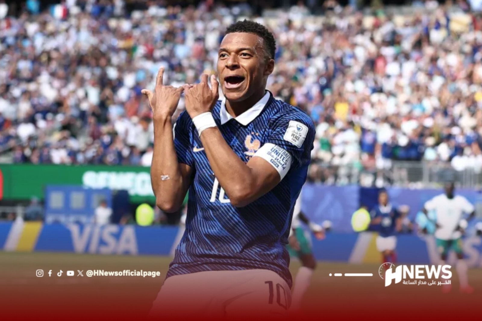Male soccer player in a blue jersey celebrates a goal with hands near his face as a full stadium cheers behind him.