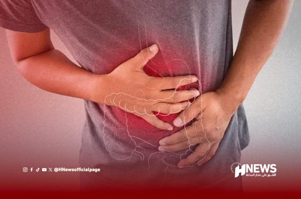 تسمم غذائي | H-NEWS آش نيوز Person holding their abdomen in pain, indicating stomach discomfort in a gray shirt.