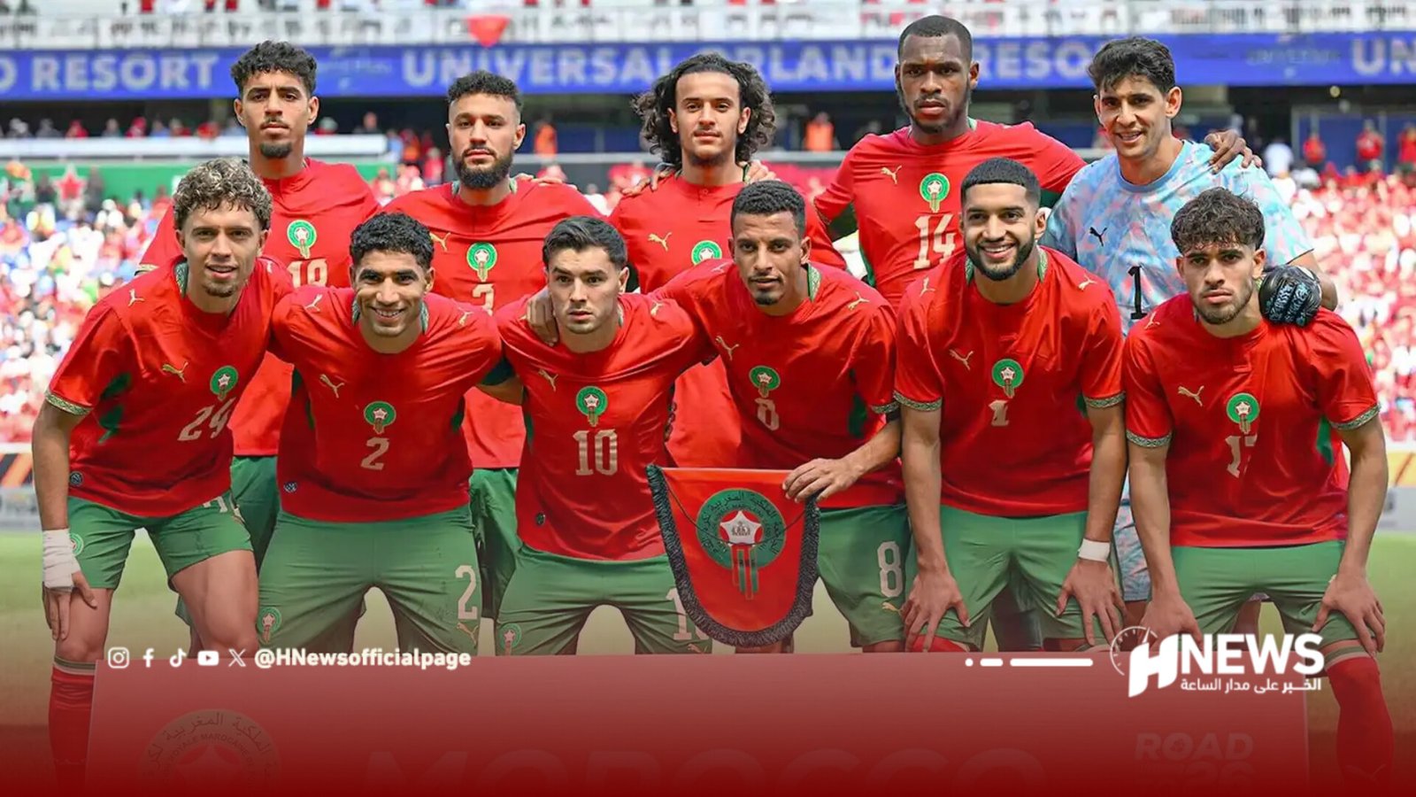 Morocco national football team players in red shirts and green shorts pose for a group photo on the field before a match.