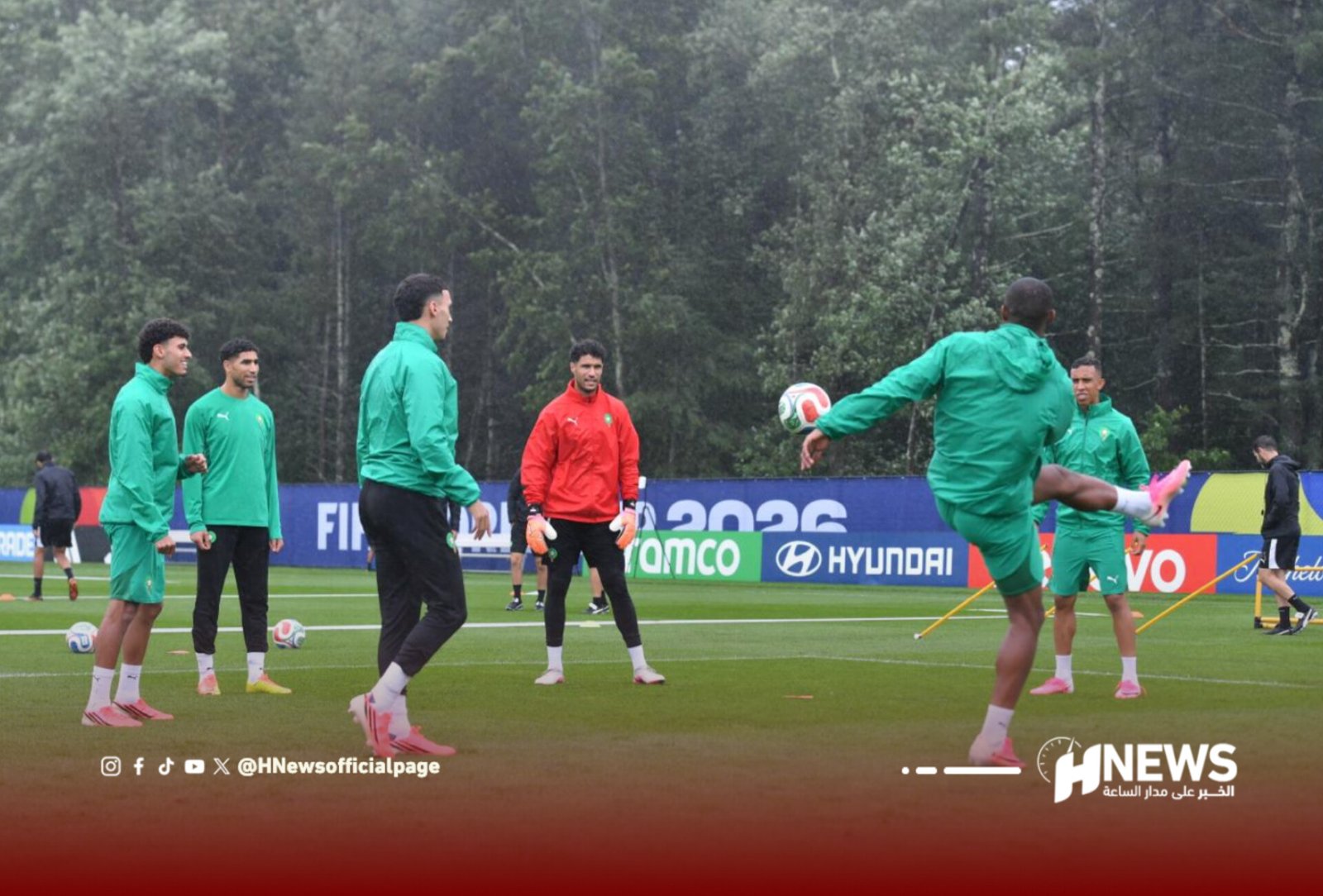 Soccer players in green training outfits on a practice field, with one player performing a kick while teammates watch.