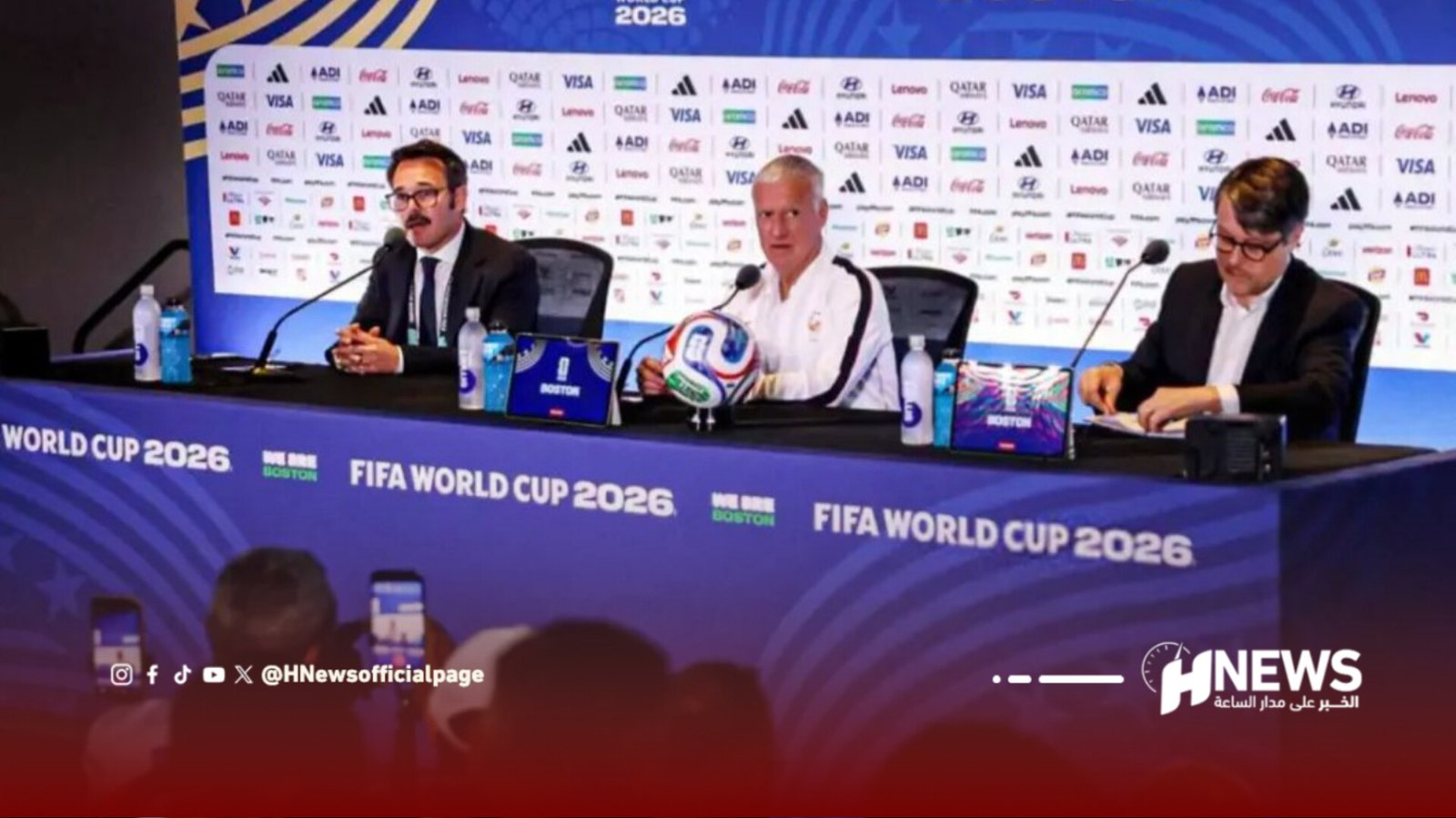Panel at FIFA World Cup 2026 press conference featuring three men seated at a blue bannered table with a soccer ball centerpiece and sponsor logos behind them, Boston branding visible.