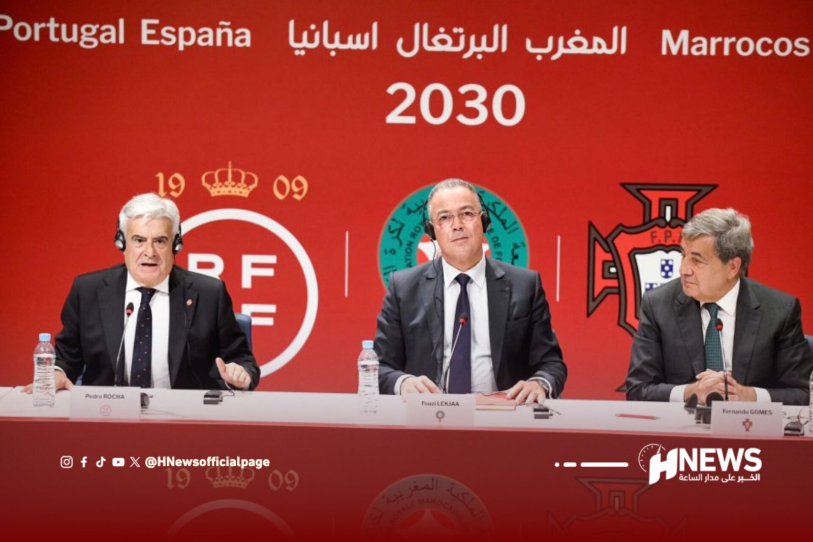 Three men in suits sit at a panel desk during a press conference, microphones in front of them, against a red backdrop reading 'Portugal Espanha Marrocos 2030' with a large HNews logo to the right.