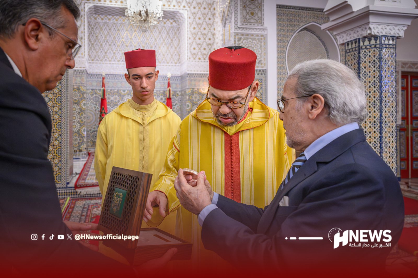 Three men, two in traditional yellow robes with red fezzes and one in a suit, examine an ornate item inside a richly tiled room.