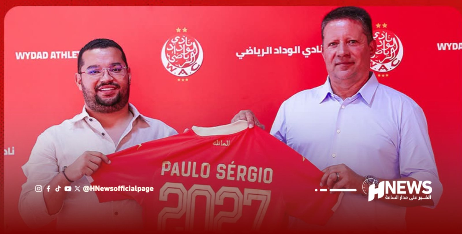 Two men in light shirts hold up a red sports jersey with the name Paulo Sergio, posing in front of a red backdrop with club logos and Arabic text.