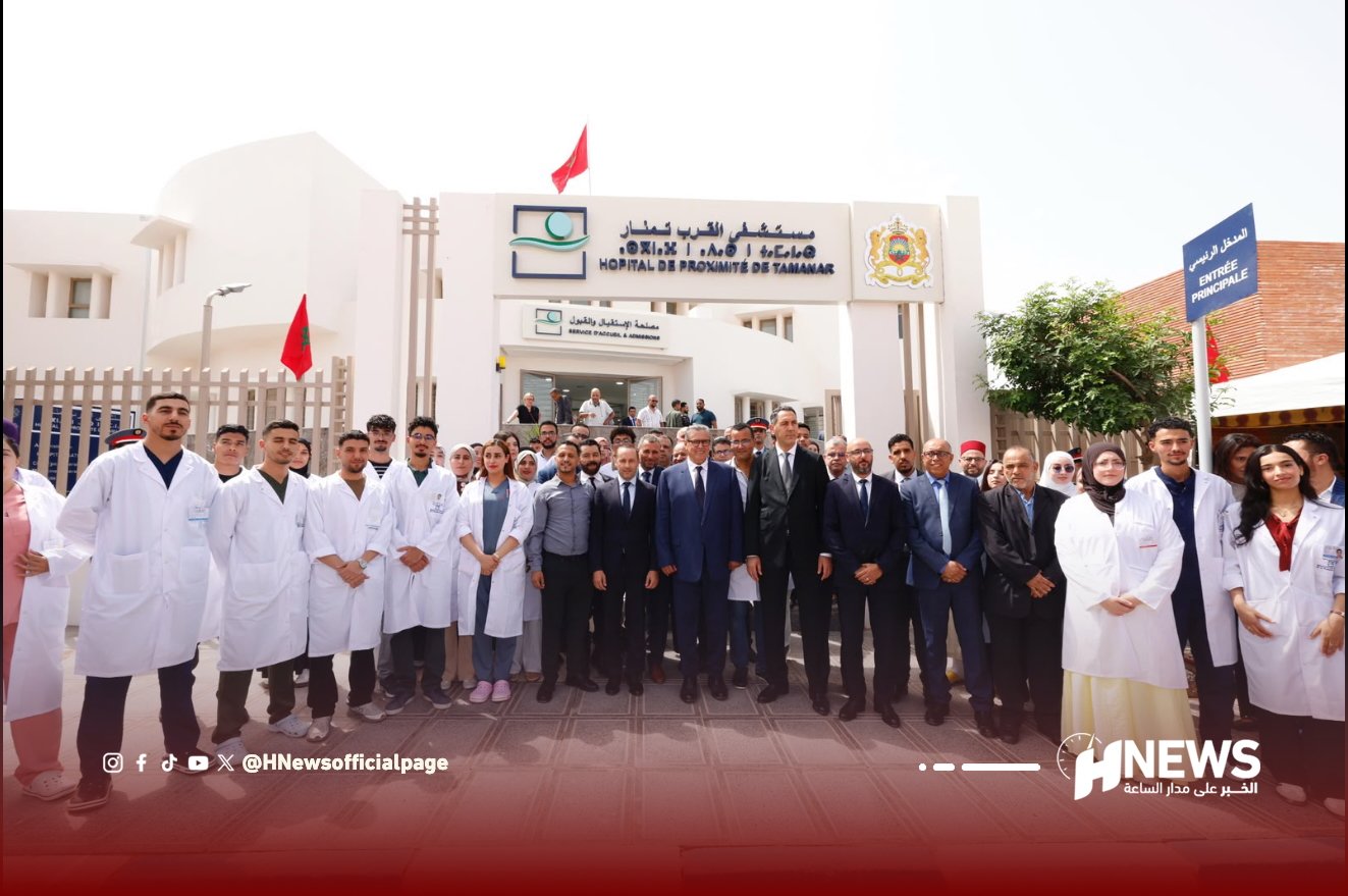 أخنوش مستشفى 2 | H-NEWS آش نيوز Group of doctors and staff in white coats posing outside a hospital entrance, with a crowd in front of the building office and signage visible behind them.