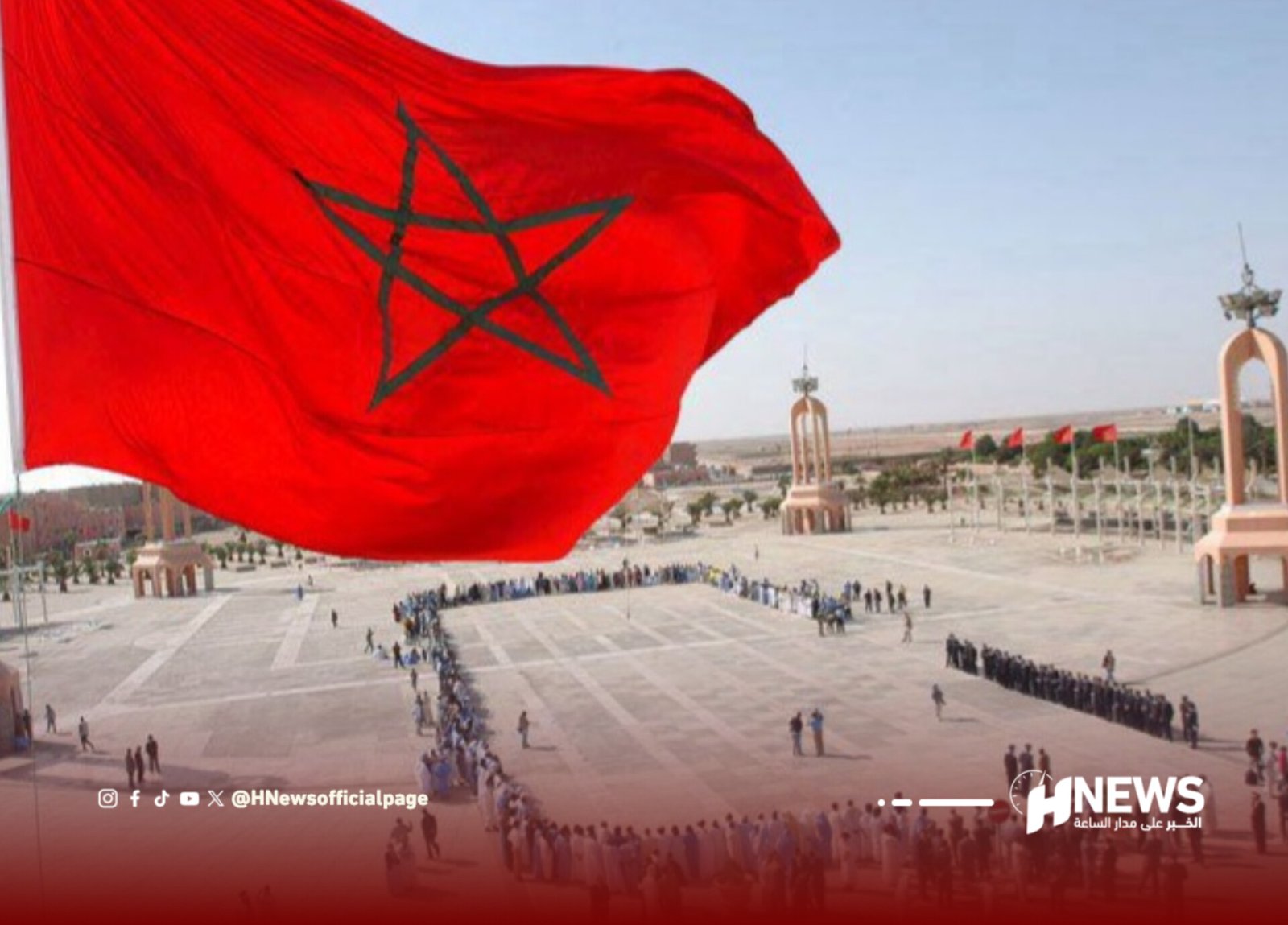 Large red Moroccan flag with green pentagram waving above a ceremonial plaza and lined troops or spectators in the background.
