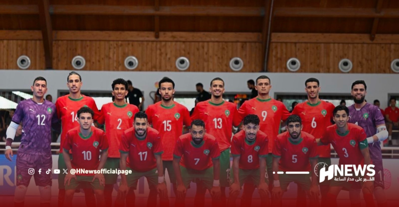 Team of Moroccan futsal players posing for a group photo indoors, wearing red jerseys with numbers and green trim (goalkeepers in purple).