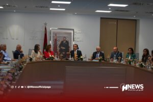 Formal meeting around a curved conference table with officials; Moroccan flag and a large framed portrait behind the speakers are visible in a government-style room.