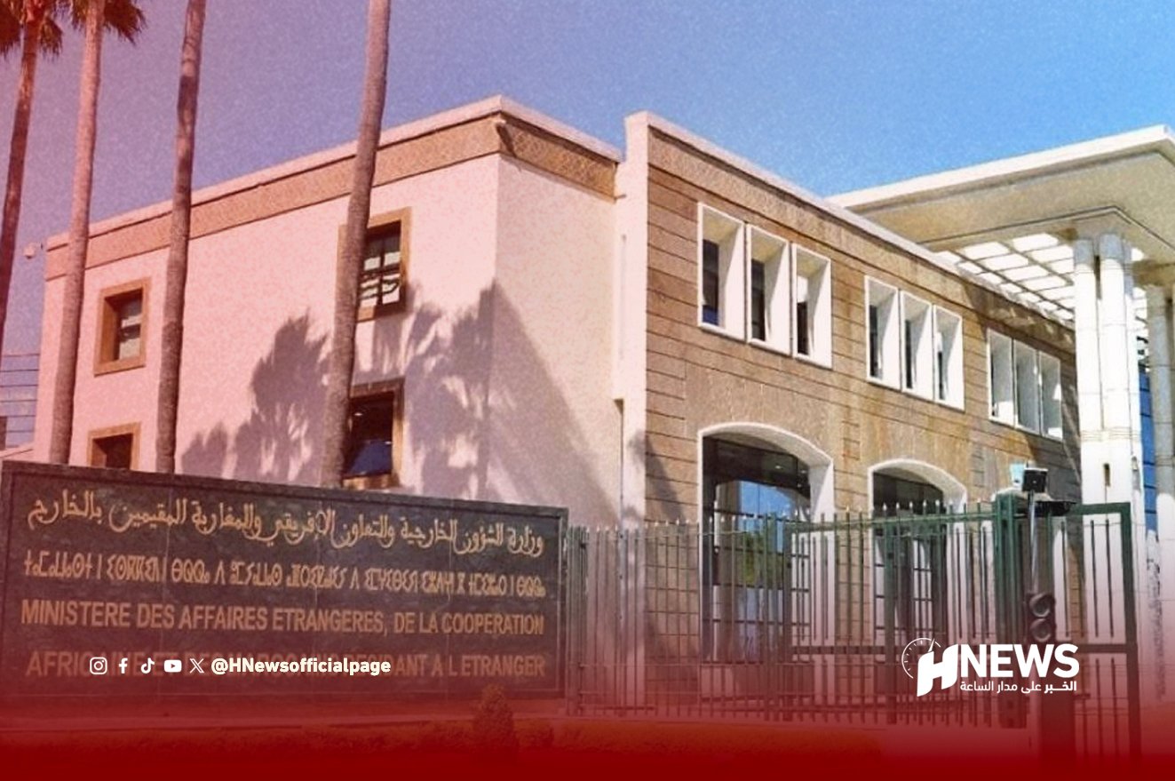 Government building behind a metal fence, with a dual-language sign in Arabic and French in front (Ministère des Affaires Étrangères, de la Coopération) and a modern facade with large windows and palm trees nearby.